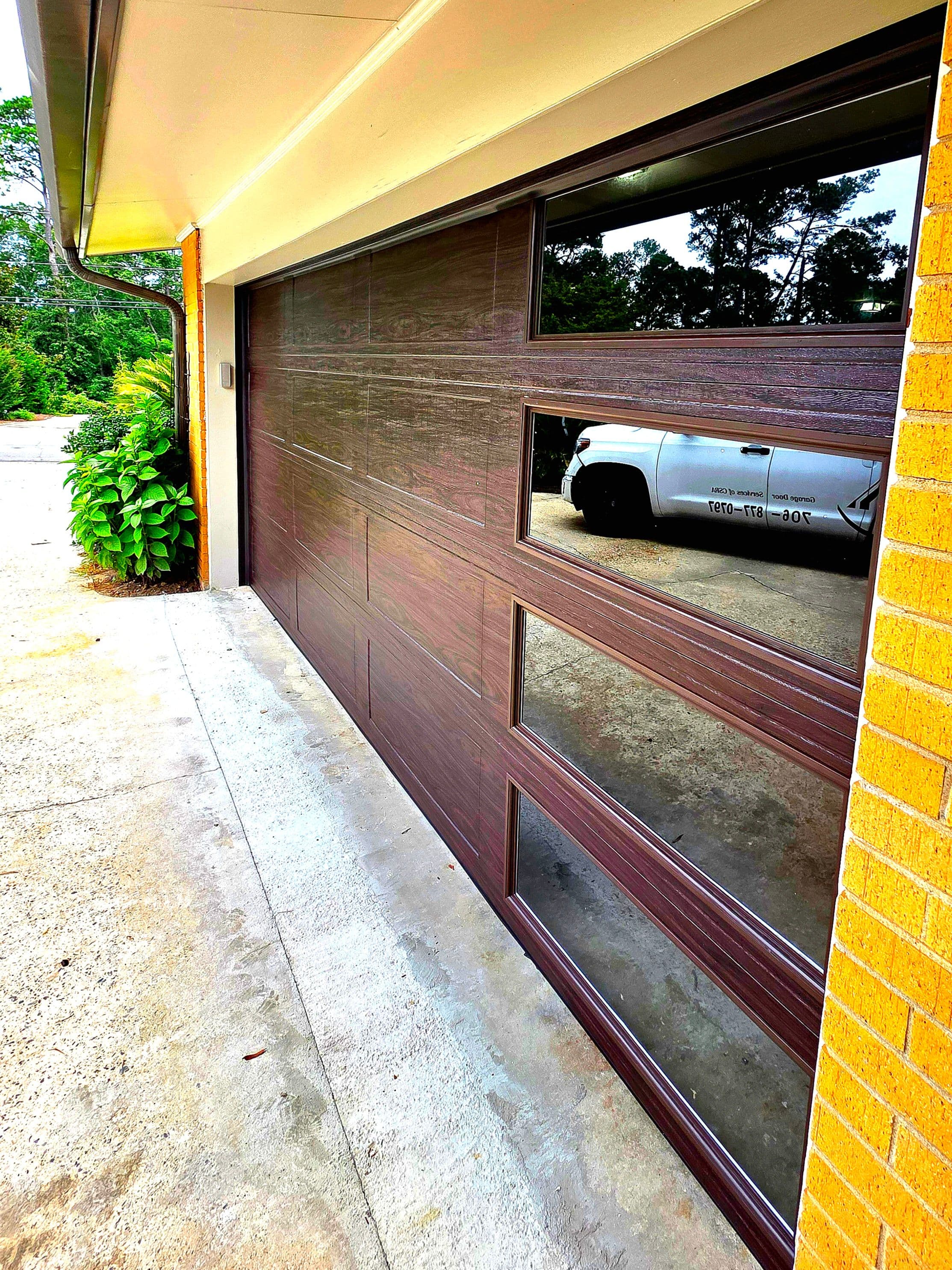 Modern wooden garage door with glass panels and sleek design, enhancing curb appeal.