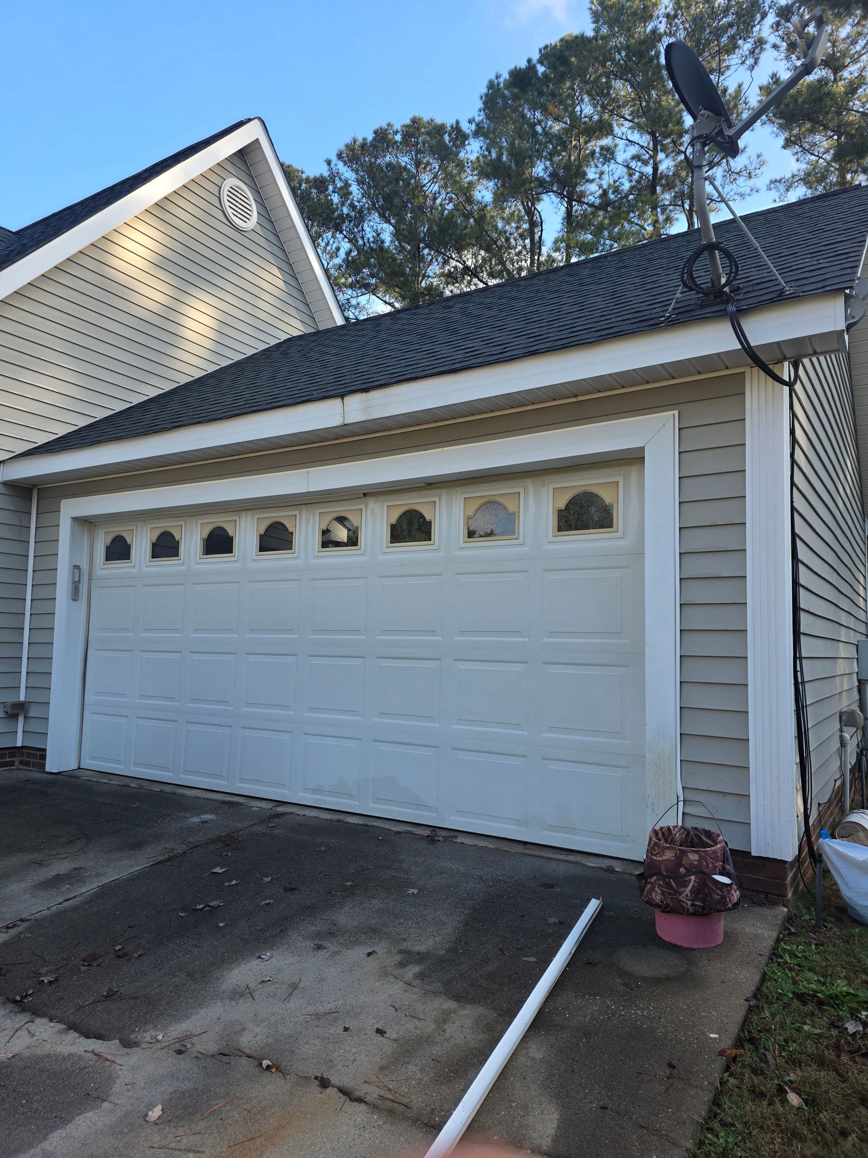 White garage door with eight windows, attached to a modern home, surrounded by greenery.