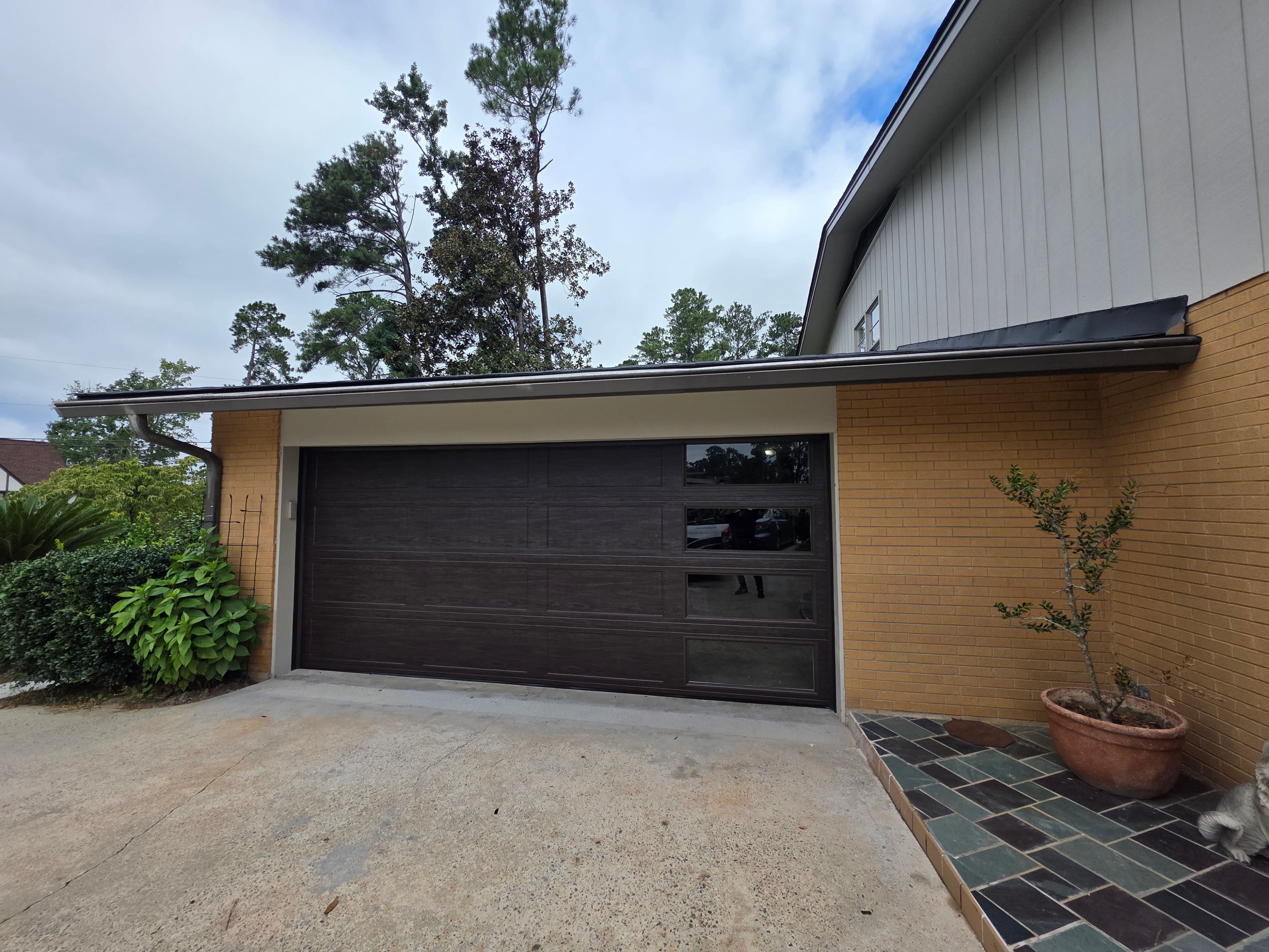 Modern home exterior featuring a sleek brown garage door and landscaped entryway.
