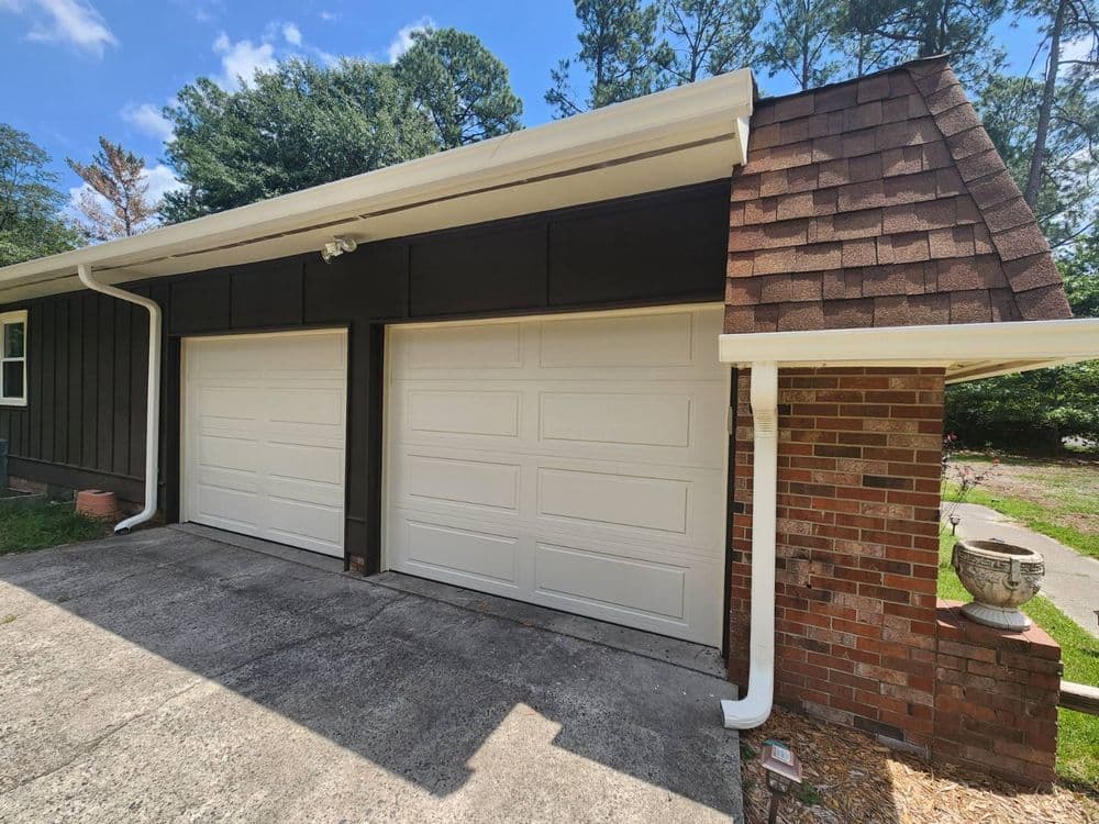 Modern home garage with white doors and brick detailing on a sunny day.
