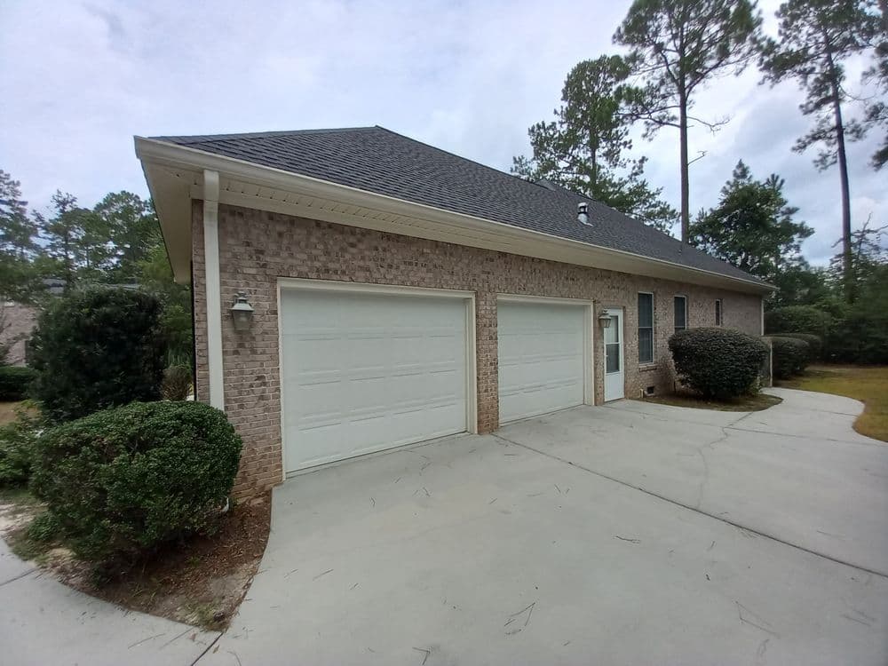 House exterior featuring a brick facade, double garage doors, and landscaped driveway.