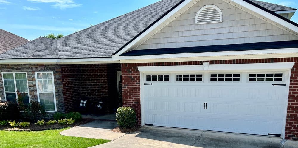 Modern brick home with a white garage door, manicured lawn, and stylish roofline on a sunny day.