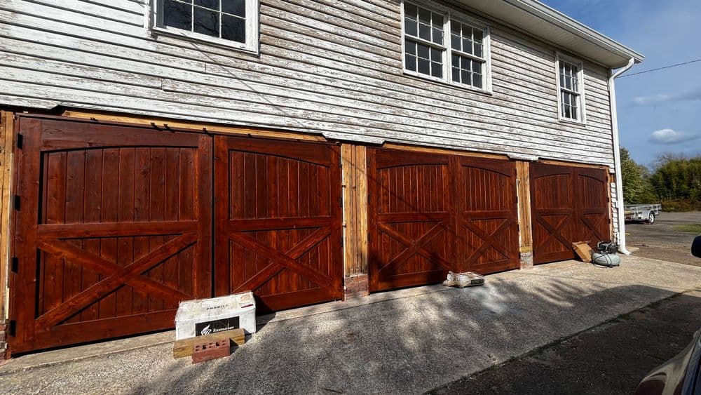 Rustic wooden garage doors installed on a weathered building exterior. Ideal for traditional homes.
