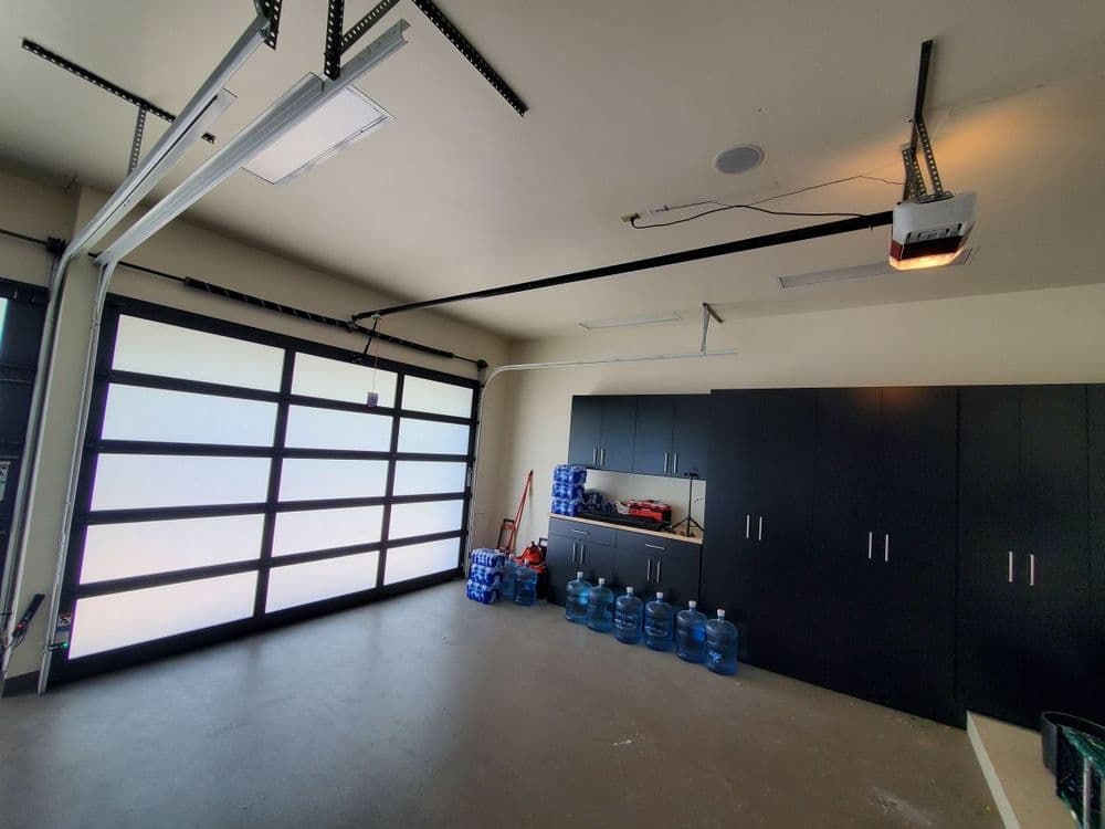 Spacious garage interior with modern overhead door and storage cabinets, featuring water bottles.