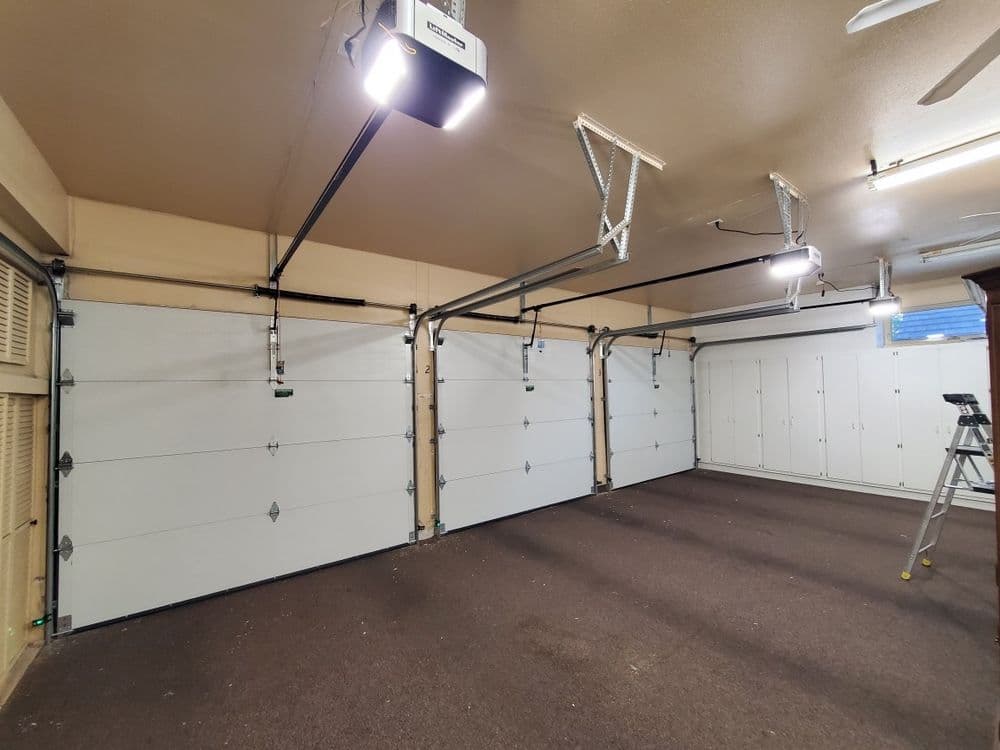Spacious, well-lit garage with white doors and a ladder against the wall.