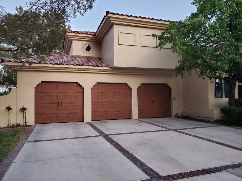 Modern home exterior with three wooden garage doors and landscaped yard.