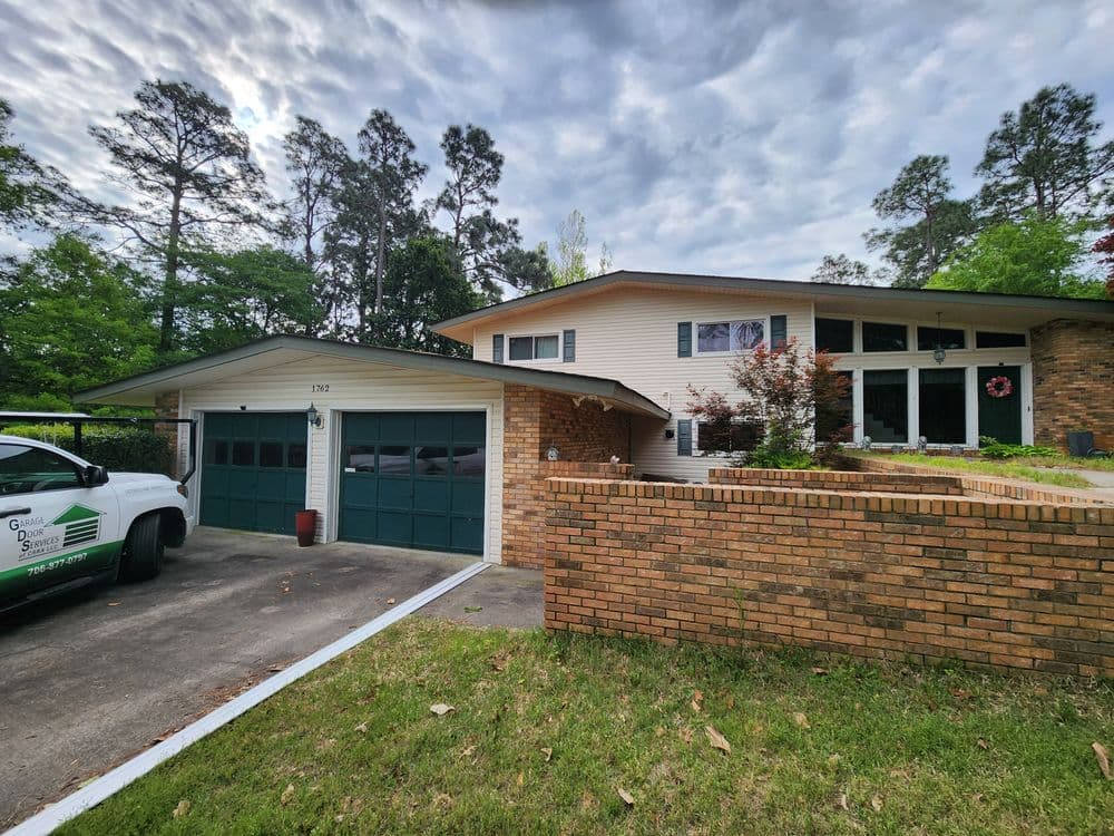 Two-story suburban house with a garage, manicured lawn, and cloudy sky.