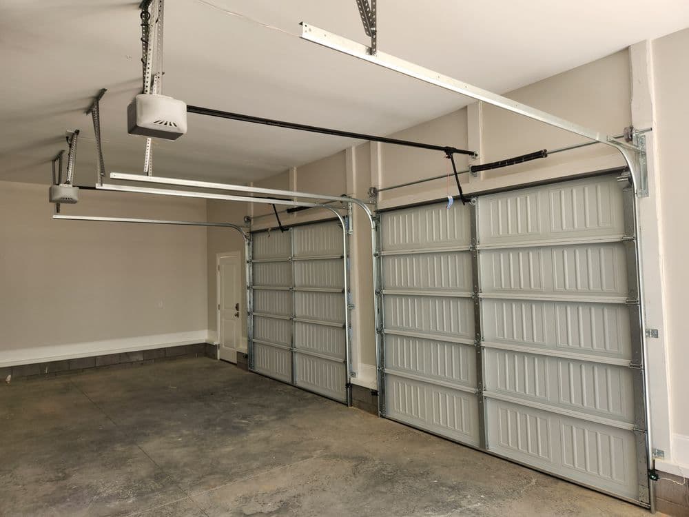 Modern garage interior with two overhead doors and ceiling-mounted storage systems.