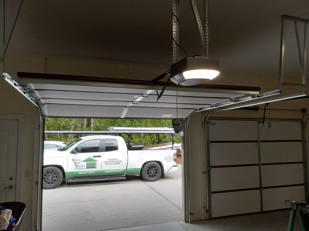 Garage interior with open door, showcasing a service truck parked outside. Bright overhead lighting.