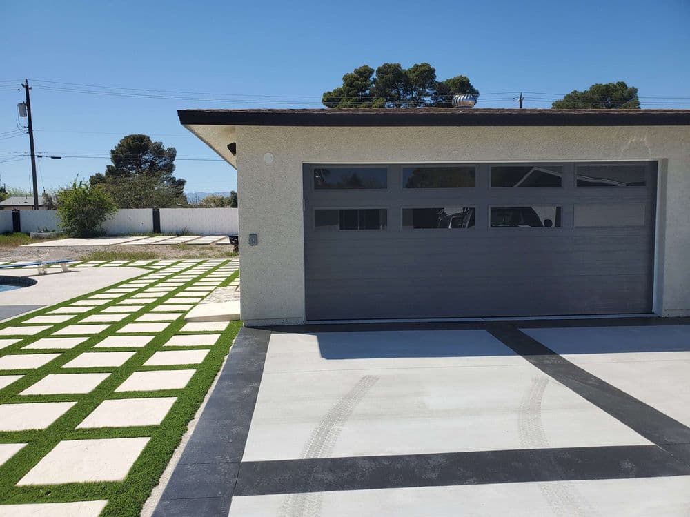 Modern garage door with horizontal panels, surrounded by landscaped driveway and green turf.